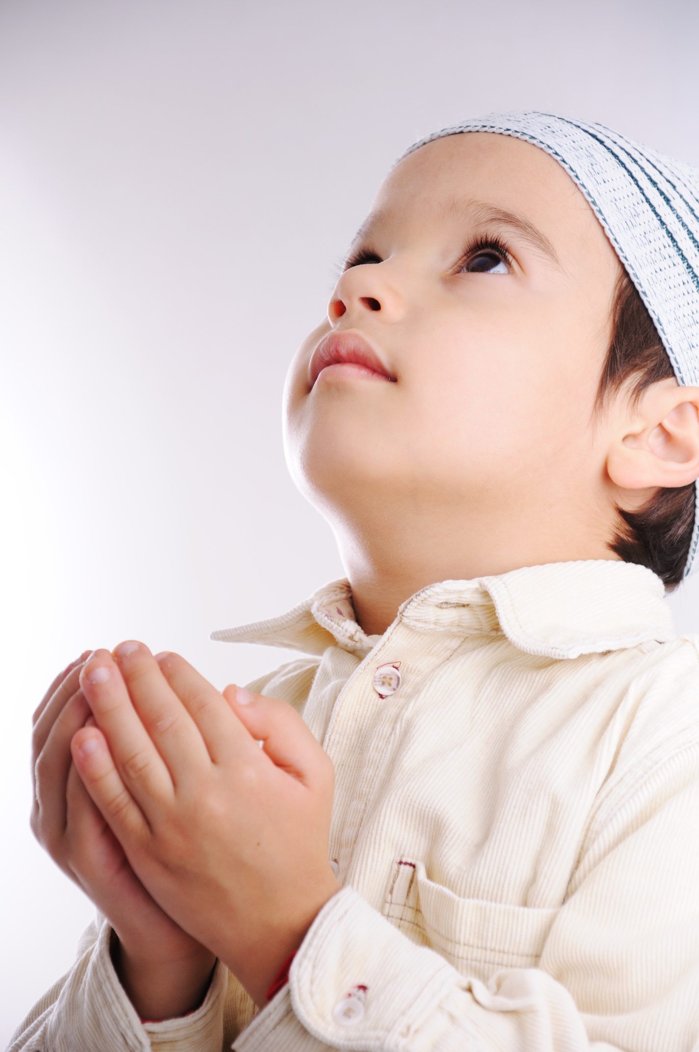 Muslim little cute kid with hat while praying to Allah